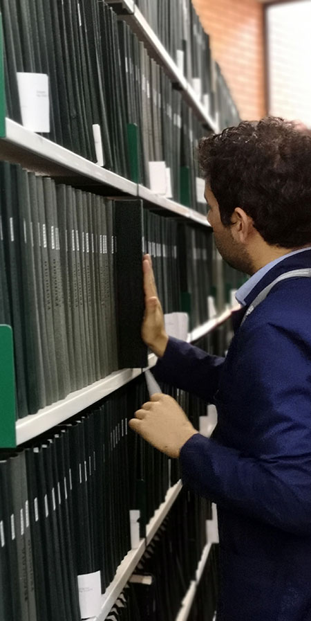 Foto de hombre acomodando protocolos notariales en estantería